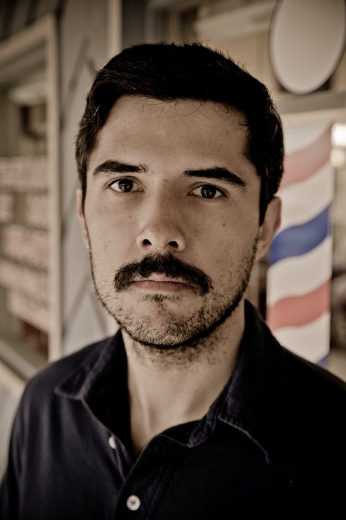 A man before the shave standing outside the barbershop.