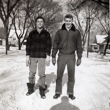 Two men, following the man's guide, standing in the snow, showcasing appropriate cold weather dressing.