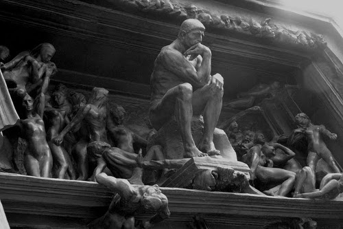 A black and white photo of a statue of the thinker, embodying manliness and contemplating life's lessons.