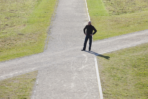 A man standing on a path in a field, contemplating life's biggest decisions.