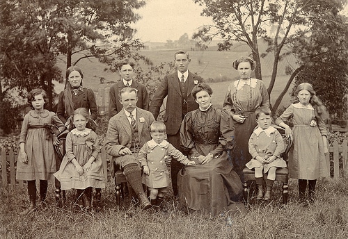 An old photo of a family posing in front of a fence, capturing the essence of familial bonds and heritage.