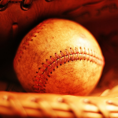 A baseball is resting in a well-worn baseball glove.