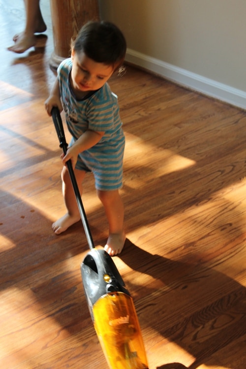 Young boy doing chores vacuuming floor. 