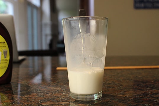 Pour Milk into the glass place a spoon in the glass.
