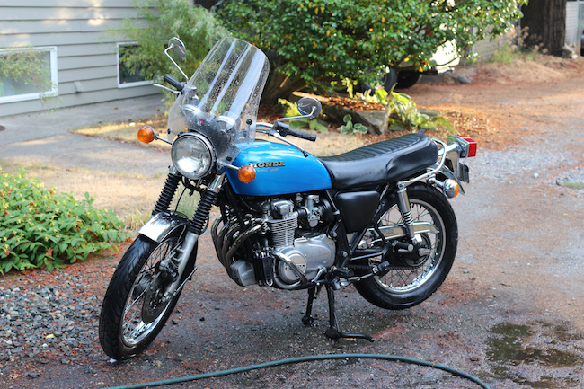 A blue motorcycle parked on a driveway next to a house.
