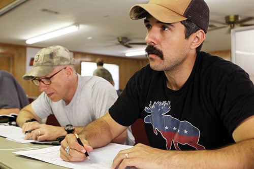 Men plotting a line with pencil and navigating the map.