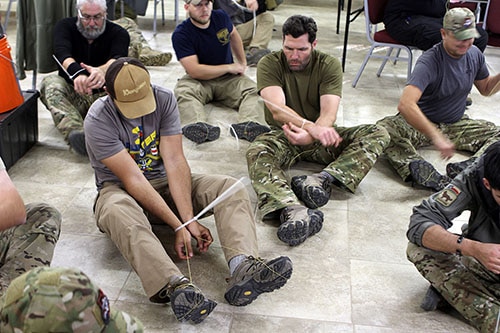 Men using a kevlar string through zip ties.