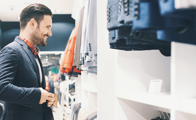 A man browsing through t-shirts and jeans in a clothing store, searching for his perfect style.