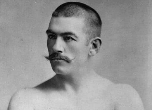 A black and white photo of a man with a mustache showcasing his masculinity.