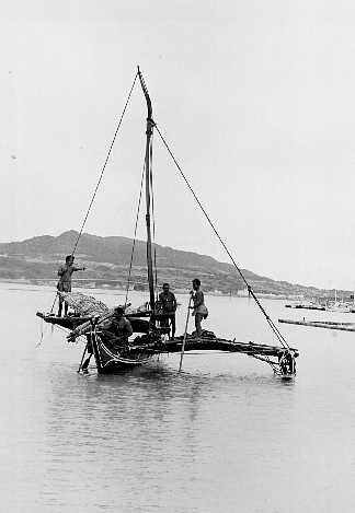 Trukese native Indian men on sailboat in water. 