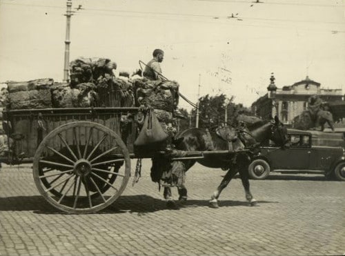 Vintage man in carriage horse pulled wagon full of things.