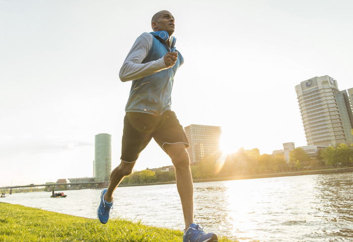 A man jogging near a river for his workout.