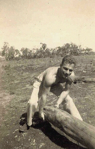 Building resiliency, a man lifts a log in a field.