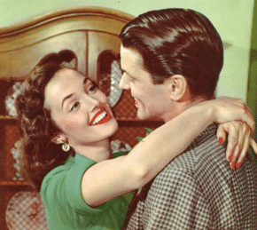 A man and woman hugging in front of a dresser.