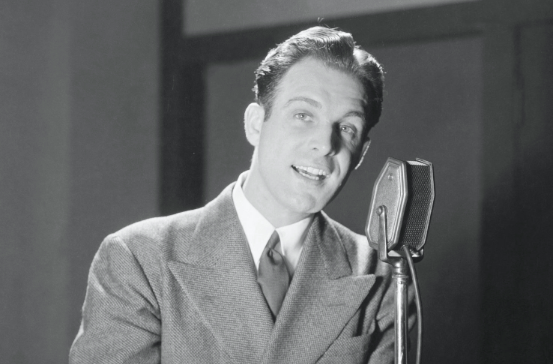 A man in a suit is speaking into a microphone to improve his podcast.